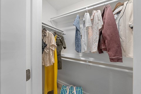 a walk in closet with clothes hanging on a rack